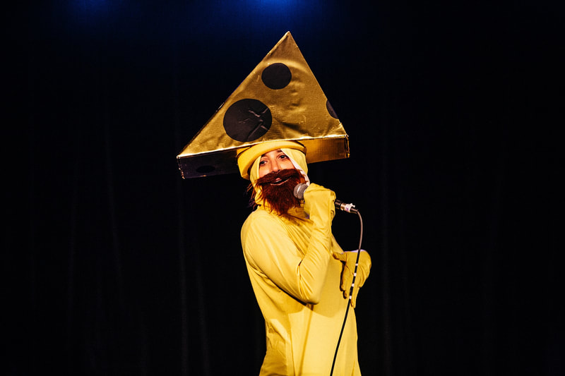 Mr. Cheesehead (Debbie Zukerman) singing "Another one bites the Cheese" in You'll Never Guess Where I Hid the Cheese, Sydney Fringe 2017